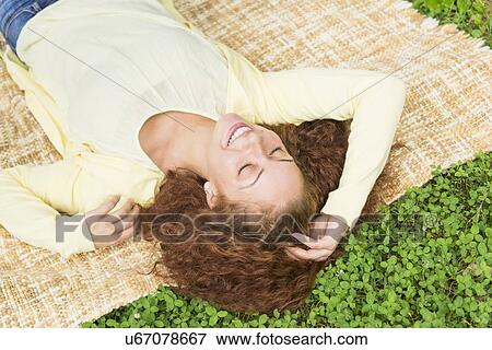Woman lying on grass in park View Large Photo Image Stock Photo - Woman lying on grass in park. Fotosearch