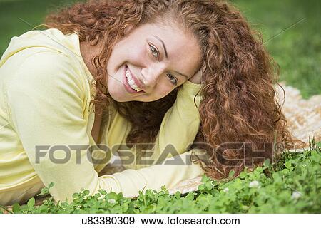 Stock Photo - Woman lying on grass in park. Fotosearch