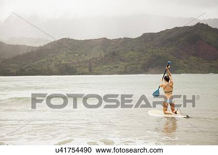 Stock Image - Woman paddling on shallow water. Fotosearch