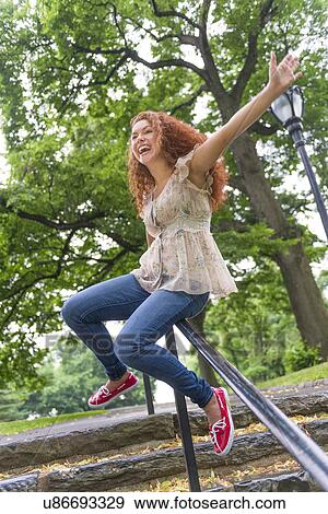 Stock Photo - Woman sliding on railing in park. Fotosearch