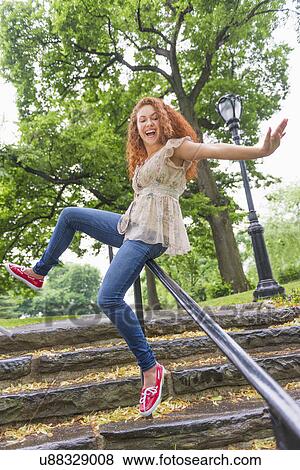 Stock Photo - Woman sliding on railing in park. Fotosearch