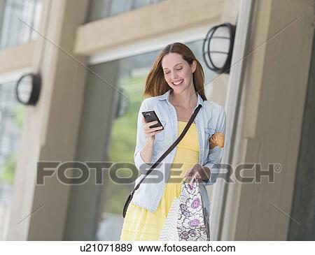 Stock Photo - Woman with shopping bags using phone. Fotosearch
