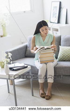 Stock Image - Woman with stack of books at home. Fotosearch