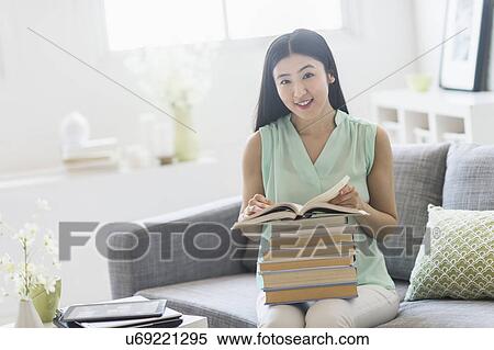 Stock Photography - Woman with stack of books at home. Fotosearch