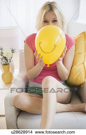 Picture - Young woman blowing balloon. Fotosearch