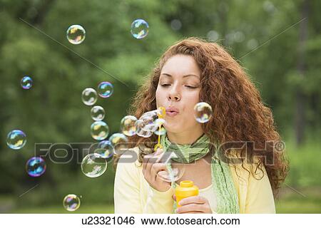Young woman blowing bubbles in park View Large Photo Image Stock Photograph - Young woman blowing bubbles in park. Fotosearch