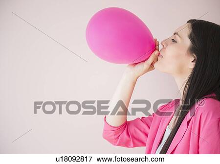 Young woman blowing pink balloon View Large Photo Image Stock Photo - Young woman blowing pink balloon. Fotosearch