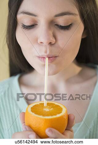 Young woman drinking orange juice from orange fruit View Large Photo Image Picture - Young woman drinking orange juice from orange fruit. Fotosearch