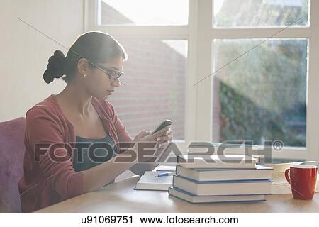 Stock Image - Young woman having coffee break during studying. Fotosearch