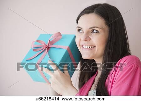 Picture - Young woman holding gift box. Fotosearch