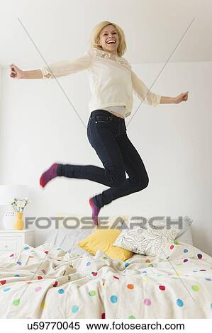 Young woman jumping on bed View Large Photo Image Stock Photography - Young woman jumping on bed. Fotosearch