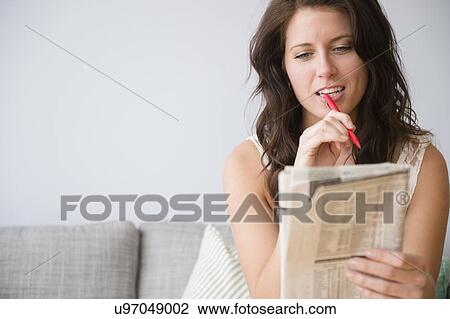 Young woman on sofa doing crossword puzzle View Large Photo Image Stock Image - Young woman on sofa doing crossword puzzle. Fotosearch