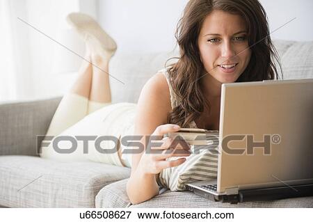 Young woman on sofa doing online shopping View Large Photo Image Stock Photo - Young woman on sofa doing online shopping. Fotosearch