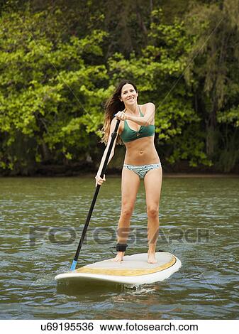 Stock Photograph - Young woman paddling in sea. Fotosearch
