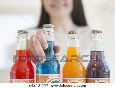 Young woman reaching for colorful bottles of soda View Large Photo Image Stock Photo - Young woman reaching for colorful bottles of soda. Fotosearch