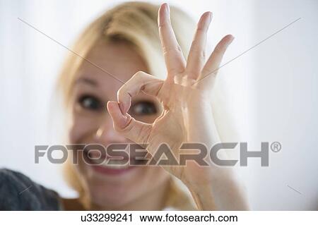 Stock Image - Young woman showing ok sign. Fotosearch
