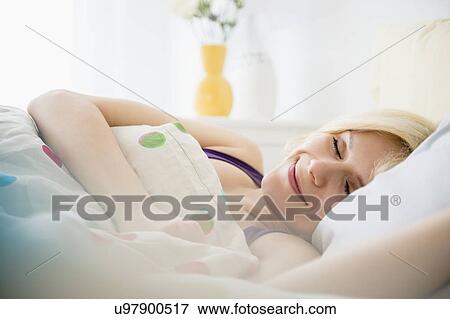 Stock Photo - Young woman sleeping in bed. Fotosearch