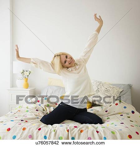 Stock Image - Young woman stretching in bed. Fotosearch