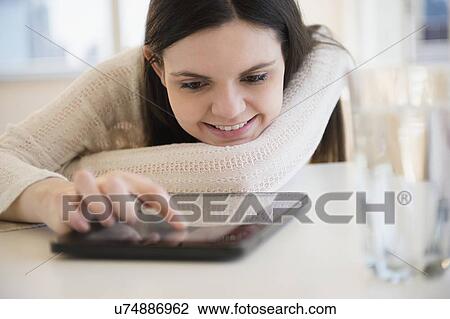 Stock Image - Young woman using digital tablet. Fotosearch