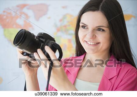 Stock Photo - Young woman using dslr camera. Fotosearch