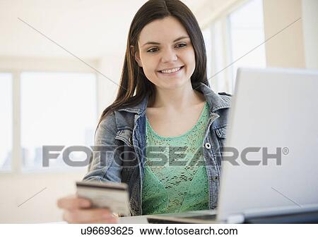 Stock Photography - Young woman using laptop for online shopping. Fotosearch