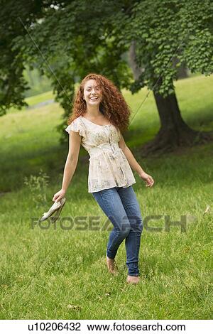 Stock Image - Young woman walking in park. Fotosearch
