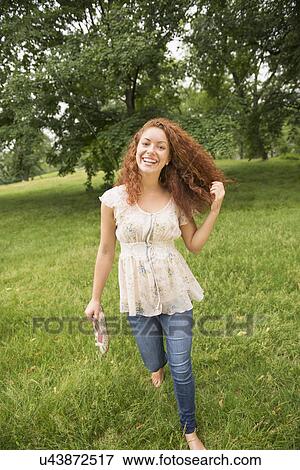 Stock Photo - Young woman walking in park. Fotosearch
