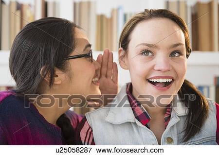 Young woman whispering to friends ear View Large Photo Image Stock Photo - Young woman whispering to friends ear. Fotosearch