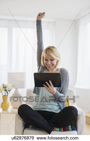 Stock Photo - Young woman with digital tablet gesturing in success. Fotosearch