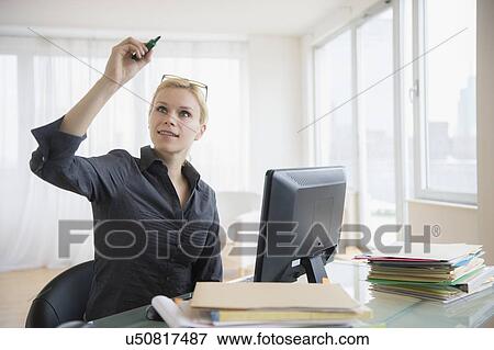 Stock Photo - Young woman working at desk in office. Fotosearch
