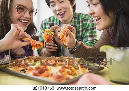 Stock Image - Young women and man eating nachos with melted cheese. Fotosearch
