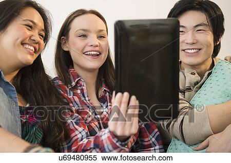 Stock Photography - Young women and man looking at digital tablet. Fotosearch