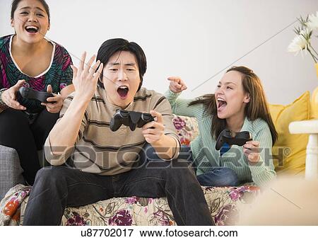 Young women and man playing video game View Large Photo Image Stock Photo - Young women and man playing video game. Fotosearch