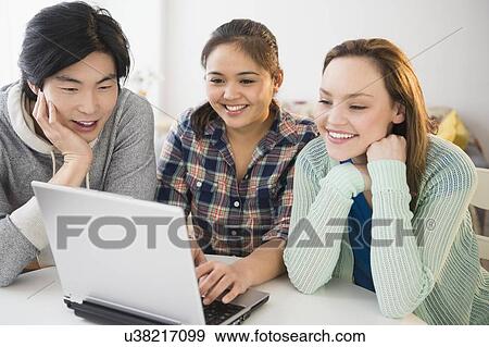 Stock Photo - Young women and man using laptop. Fotosearch