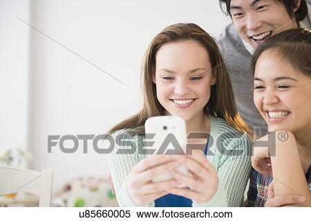 Young women and man using mobile phone View Large Photo Image Stock Photography - Young women and man using mobile phone. Fotosearch