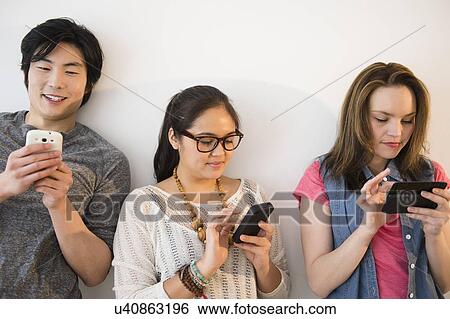 Young women and man using mobile phones View Large Photo Image Stock Photograph - Young women and man using mobile phones. Fotosearch