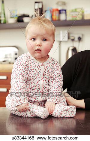 Stock Photo - Baby girl sitting on table. Fotosearch