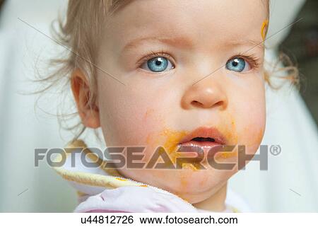 Stock Photograph - Baby girl with food on mouth. Fotosearch