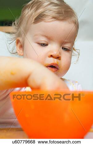 Baby girl with hand in orange bowl View Large Photo Image Stock Photo - Baby girl with hand in orange bowl. Fotosearch