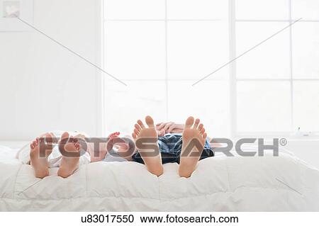 Stock Image - Bare feet of parents and baby. Fotosearch