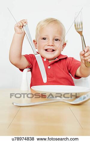 Stock Photo - Boy holding cutlery with empty plate. Fotosearch