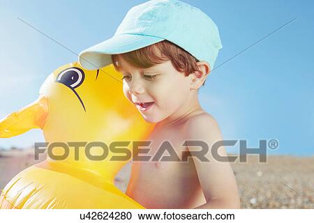 Stock Image - Boy hugging duck shaped float. Fotosearch
