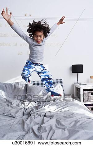 Boy jumping on bed with arms up View Large Photo Image Stock Image - Boy jumping on bed with arms up. Fotosearch