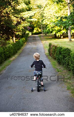Boy riding tricycle on path View Large Photo Image Stock Photo - Boy riding tricycle on path. Fotosearch