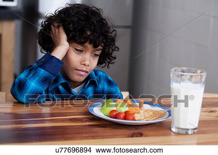 Picture - Boy staring at snacks and glass of milk. Fotosearch