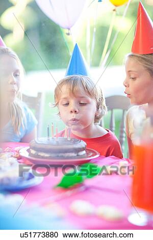 Stock Image - Brother and his sisters enjoying birthday party. Fotosearch