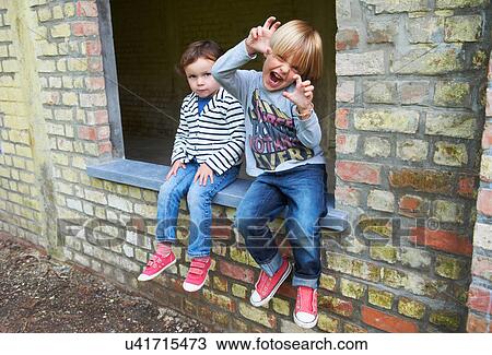 Brother and sister sitting on window sill View Large Photo Image Stock Image - Brother and sister sitting on window sill. Fotosearch