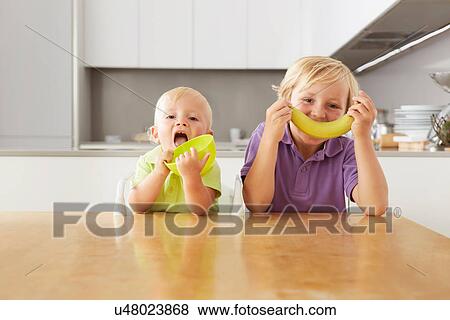 Brothers playing with bowl and banana at table View Large Photo Image Stock Photo - Brothers playing with bowl and banana at table. Fotosearch