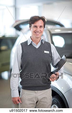 Stock Photo - Car salesman with file in showroom. Fotosearch