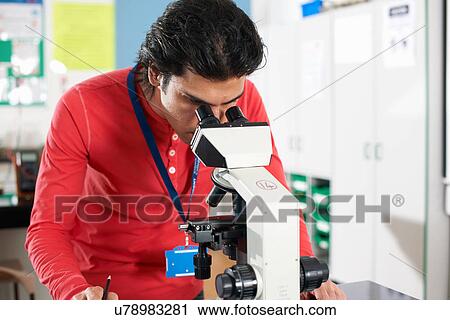 Stock Image - Chemistry student using microscope in laboratory. Fotosearch